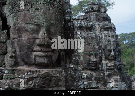 Smiling faces sont sculptées dans la pierre au Bayon, Site du patrimoine mondial de l'UNESCO à Angkor, au Cambodge. Banque D'Images