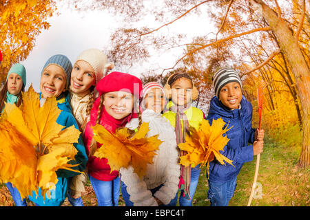 Smiling petits enfants en parc avec des feuilles jaunes Banque D'Images