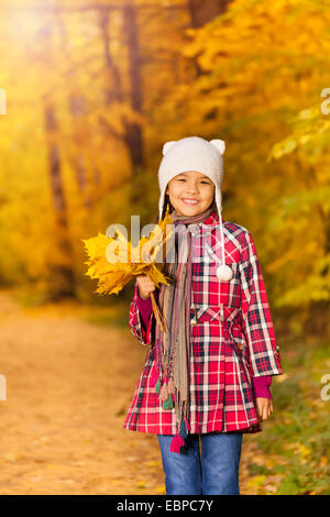 Cheerful Asian girl avec des tas de feuilles jaunes Banque D'Images
