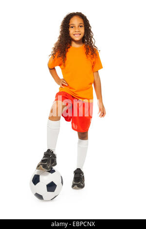 Cute girl noir debout sur un ballon de football en studio Banque D'Images