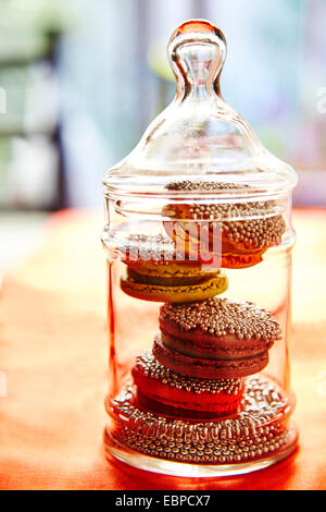 Macaron pétillant les cookies dans un bocal en verre pour les fêtes nappe orange Banque D'Images