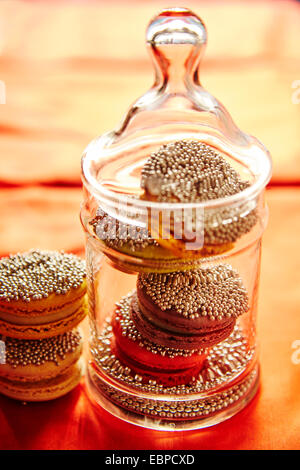 Macaron pétillant les cookies dans un bocal en verre pour les fêtes nappe orange Banque D'Images