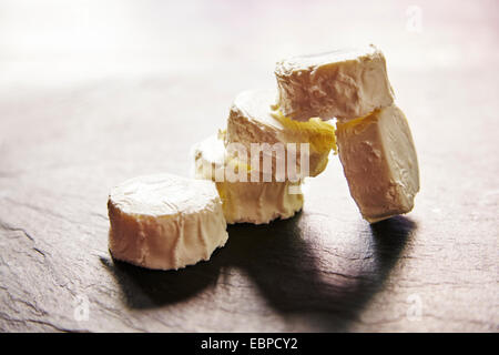 Les agriculteurs français bio fromage de chèvre couper avec un couteau sur un plateau de fromage avec un côté de craquelins de grains multiples Banque D'Images