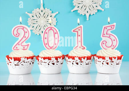 Bonne Année 2015 Red Velvet cupcakes en rouge et blanc avec des bougies allumées et décorations et snowflake Banque D'Images
