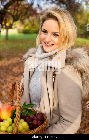 Jeune femme tenant un panier de fruits frais. Banque D'Images