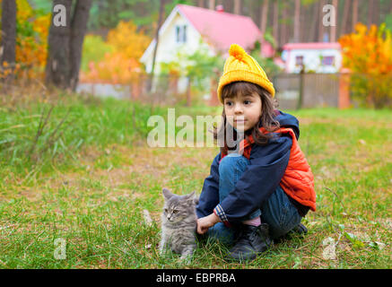 Petite fille pat le chat à l'automne en plein air Banque D'Images