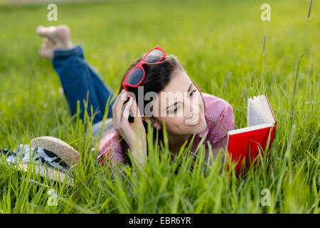 Woman lying on grass et la lecture d'un livre Banque D'Images