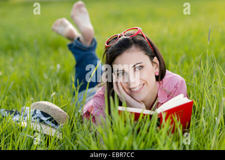 Woman lying on grass et la lecture d'un livre Banque D'Images