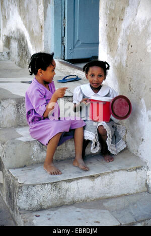 Deux petites filles africaines siégeant ensemble sur l'escalier extérieur et le chat, Tanzanie Banque D'Images