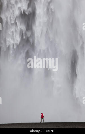 Une personne debout en face de cascade Skogafoss, Islande Banque D'Images