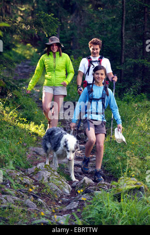 Trois jeunes gens avec chien en randonnée sur une montagne pré, France, Savoie Banque D'Images