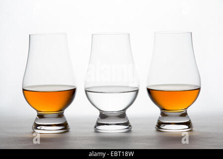 Trois verres de cristal rétroéclairé ambre clair et contenant de l'alcool. Vodka, Whisky, bourbon, cognac, etc. Banque D'Images