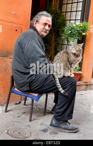 Homme avec un chat sur ses genoux assis dans une ruelle de Trastevere, l'Italie, le Trastevere, Rome Banque D'Images