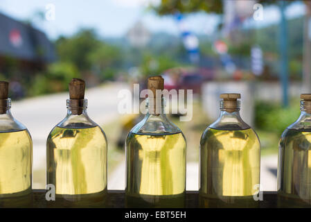 Selective focus sur une rangée de bouteilles en verre transparent rempli de liquide d'or, comme l'huile moteur, huile de cuisson, l'essence, l'essence. Banque D'Images