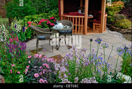 Le patio dans un jardin aquatique avec bordure de fleurs colorées et d'un coin Banque D'Images