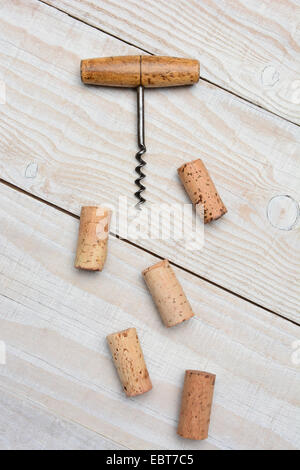 Libre d'un ancien tire-bouchon et cinq bouchons utilisés sur une table en bois blanc rustique. Format vertical à partir d'un angle élevé. Banque D'Images
