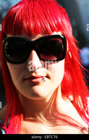 Portrait d'une jeune femme avec la couleur de cheveux rouge de couleurs vives et portant des lunettes de soleil Banque D'Images