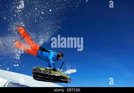 Course de l'homme sur une pente couverte de neige avec un traîneau rempli d'air, France, Savoie, La Plagne Banque D'Images