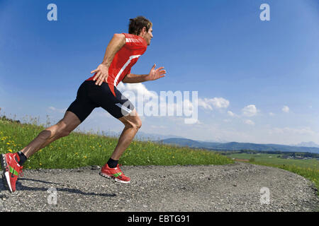 Homme qui court sur une route de gravier dans un paysage de montagne, Italie Banque D'Images