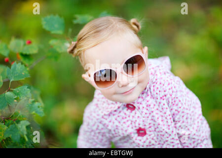 Jolie petite fille avec des lunettes de soleil dans un parc Banque D'Images