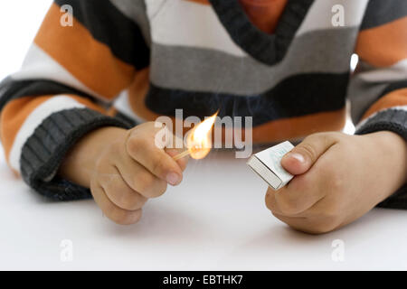 Mains d'un petit garçon ayant une allumette allumée Banque D'Images