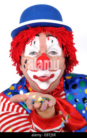 Femme habillé comme un clown confetti de soufflage Banque D'Images