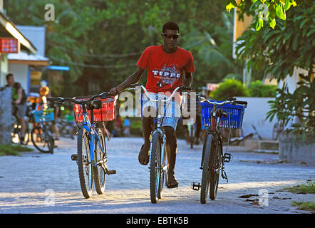 Jeune homme à vélo et transport dans chaque main un autre vélo, Seychelles Banque D'Images