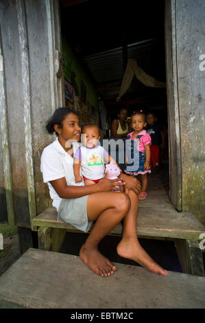 Indigènes indiens femme avec un bébé assis sur le seuil de sa maison en bois, le Honduras, La Mosquitia, Las Marias, Gracias a Dios Banque D'Images