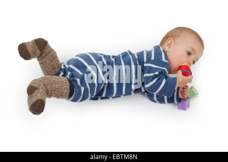 Petit enfant dans romper allongé sur le sol et jouer avec les jouets de bébé Banque D'Images