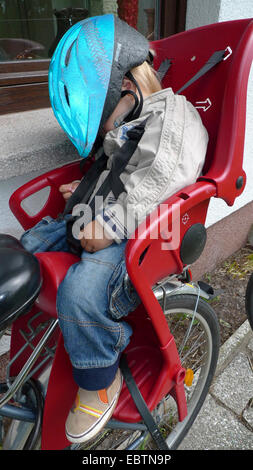 Petit garçon au retour d'un tour en vélo : deux d'alcool, l'un dormant dans le siège pour enfant sur un vélo Banque D'Images