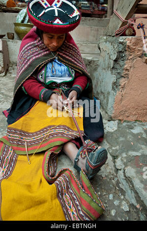 Jeune femme en costume traditionnel travaillant sur une couverture à l'atelier d'artisanat local, du Pérou, de Chincheros Banque D'Images