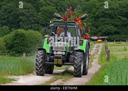 Le tracteur et la faneuse sur Trajectoire du champ, l'Allemagne, Rhénanie du Nord-Westphalie Banque D'Images