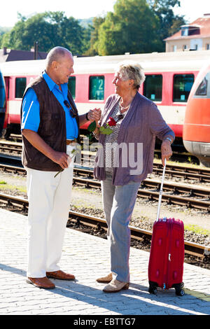 Vieux couple, l'homme dit au revoir à la femme au train d'une gare ferroviaire de la plate-forme avec une rose rouge Banque D'Images