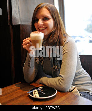 Jeune femme dans un café boire un cappuccino, France, Paris Banque D'Images