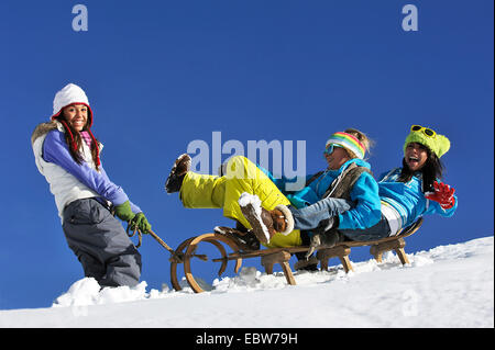 Trois jeunes filles dans la neige s'amusant avec un traîneau, France Banque D'Images