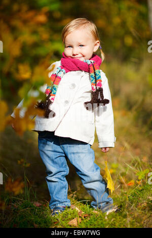 Petite fille avec l'écharpe holding autumn leaf Banque D'Images