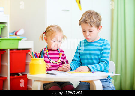 Une jeune fille et son frère le dessin dans le jardin d'enfants Banque D'Images