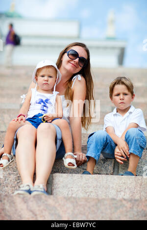 Jeune mère assise avec ses deux petits enfants sur les marches en pierre Banque D'Images