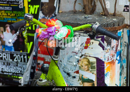 Vieux vélo en stationnement avec une décoration colorée sur le guidon à l'avant du mur de l'affiche, Allemagne Banque D'Images