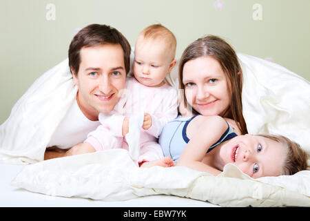 Jeune famille avec deux petits enfants au lit Banque D'Images