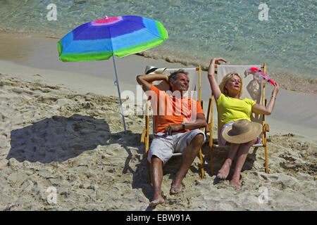 Couple de personnes âgées se trouvant dans la région de chaises en toile sur plage de sable fin, Baléares, Ibiza Banque D'Images