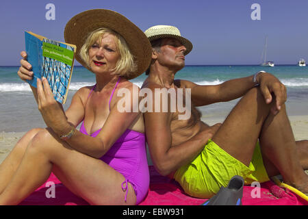 Couple de personnes âgées assis sur une serviette de plage sur la plage de sable fin, Baléares, Ibiza Banque D'Images