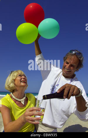 Personnes âgées couples célébrant avec ballons d'air sur la plage Banque D'Images