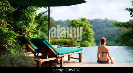 Une jeune femme assise à la piscine et admirer la vue Banque D'Images