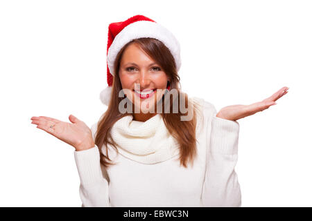 Jolie femme portant un chapeau de Père Noël rouge de fête, se blottissant dans son polo d'hiver chaud du cou avec un charmant sourire amical Banque D'Images