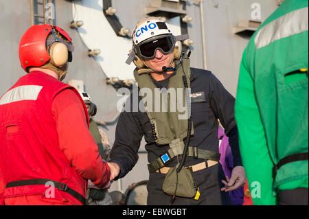 Chief of Naval Operations Adm. Jonathan Greenert portant un casque de vol, du côté de la Marine accueille les garçons à bord du porte-avions nucléaire USS Carl Vinson après son arrivée le jour de Thanksgiving avec sa femme Darleen pour passer du temps avec l'équipage pour la maison de vacances le 27 novembre 2014 dans la mer d'Oman. Banque D'Images