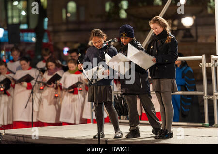 Londres, Royaume-Uni. 4 Décembre, 2014. L'assemblée annuelle de l'éclairage de l'arbre de Noël de Trafalgar Square a eu lieu aujourd'hui, organisé par le maire de la ville de Westminster, la Rcbd Audrey Lewis, qui a invité le maire d'Oslo pour allumer les lumières de Noël. L'arbre est donné par la Ville d'Oslo pour la population de Londres chaque année en signe de gratitude pour le soutien britannique pendant la Seconde Guerre mondiale. Sur la photo : Trois écoliers de Sainte Marie des Anges de l'école primaire catholique prendre son tour à réciter un poème écrit spécialement pour l'occasion par le poète national de l'Écosse Liz Lochhead. © Lee Thomas/Alamy Banque D'Images