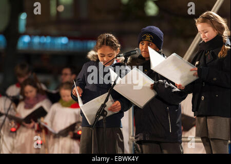 Londres, Royaume-Uni. 4 Décembre, 2014. L'assemblée annuelle de l'éclairage de l'arbre de Noël de Trafalgar Square a eu lieu aujourd'hui, organisé par le maire de la ville de Westminster, la Rcbd Audrey Lewis, qui a invité le maire d'Oslo pour allumer les lumières de Noël. L'arbre est donné par la Ville d'Oslo pour la population de Londres chaque année en signe de gratitude pour le soutien britannique pendant la Seconde Guerre mondiale. Sur la photo : Trois écoliers de Sainte Marie des Anges de l'école primaire catholique prendre son tour à réciter un poème écrit spécialement pour l'occasion par le poète national de l'Écosse Liz Lochhead. © Lee Thomas/Alamy Banque D'Images