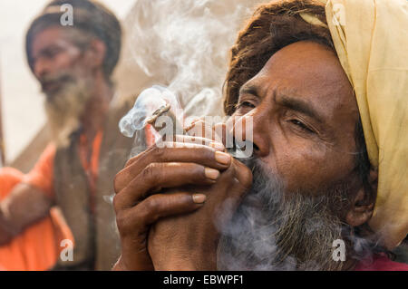 Udaisin Sadhu, saint homme, fumer de la marihuana au Sangam, le confluent des fleuves Ganges, Yamuna et Saraswati Banque D'Images