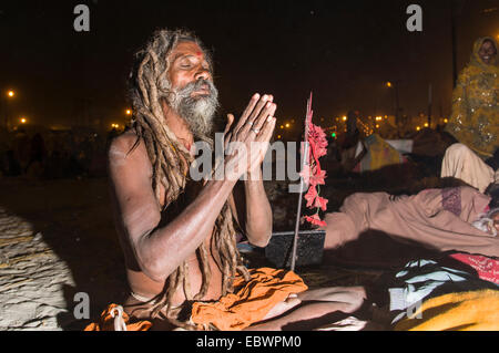 Shiva sadhu, saint homme, assis et en priant la nuit au Sangam, le confluent des fleuves Ganges, Yamuna et Saraswati Banque D'Images